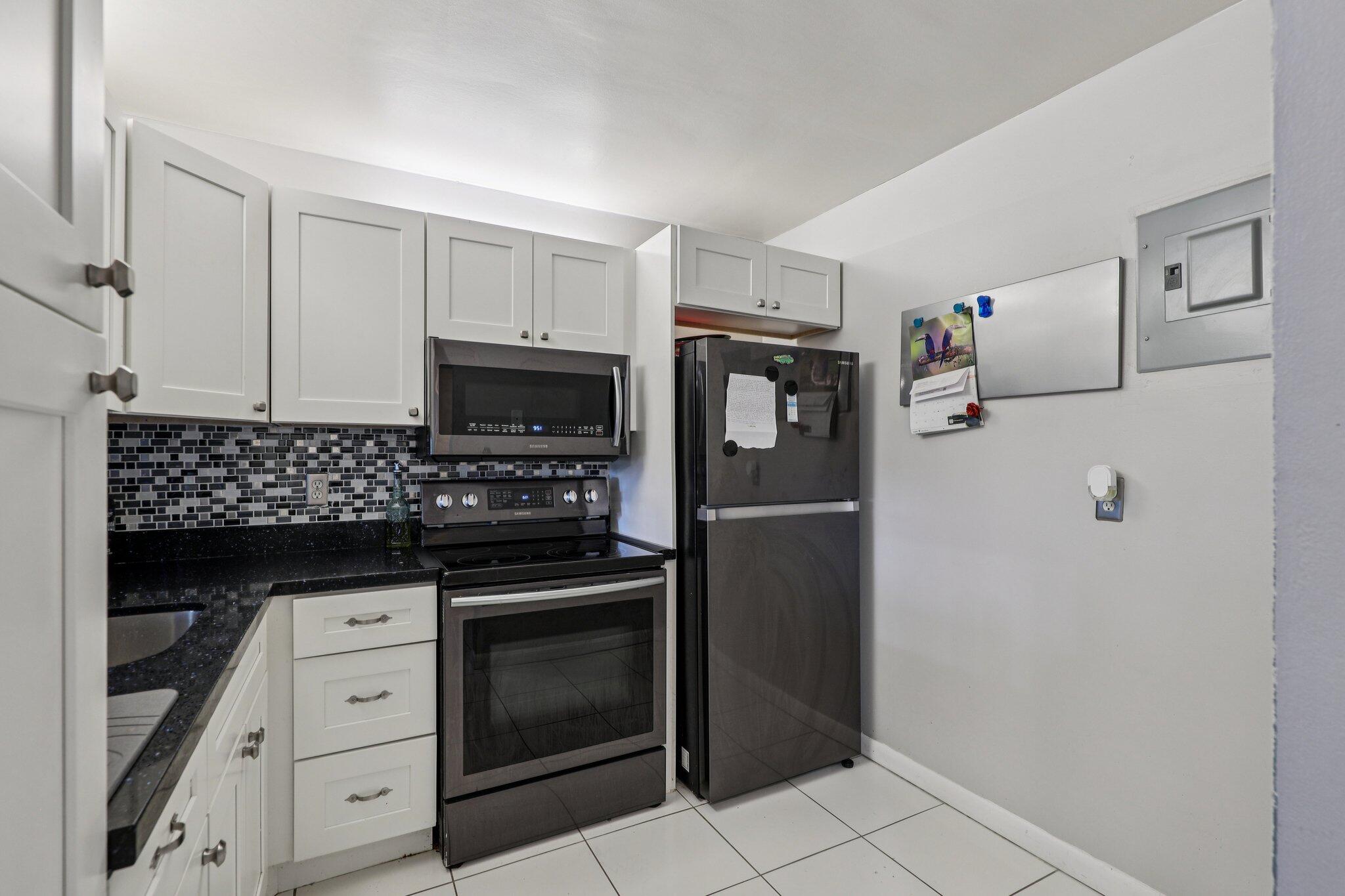 6500 Cypress Road, Unit 508 Plantation, FL 33317 - Photo 7 of 32 a kitchen with white cabinets and stainless steel appliances