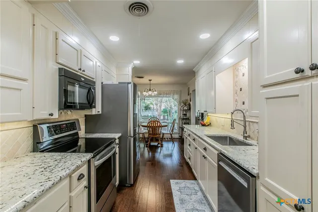 a large kitchen with stainless steel appliances granite countertop a lot of counter space and wooden floor