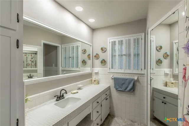 a bathroom with a double vanity sink mirror and bathtub