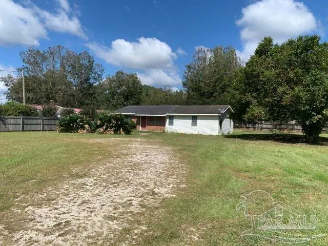 a front view of house with yard and trees in the background