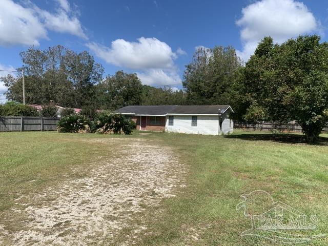a front view of house with yard and trees in the background