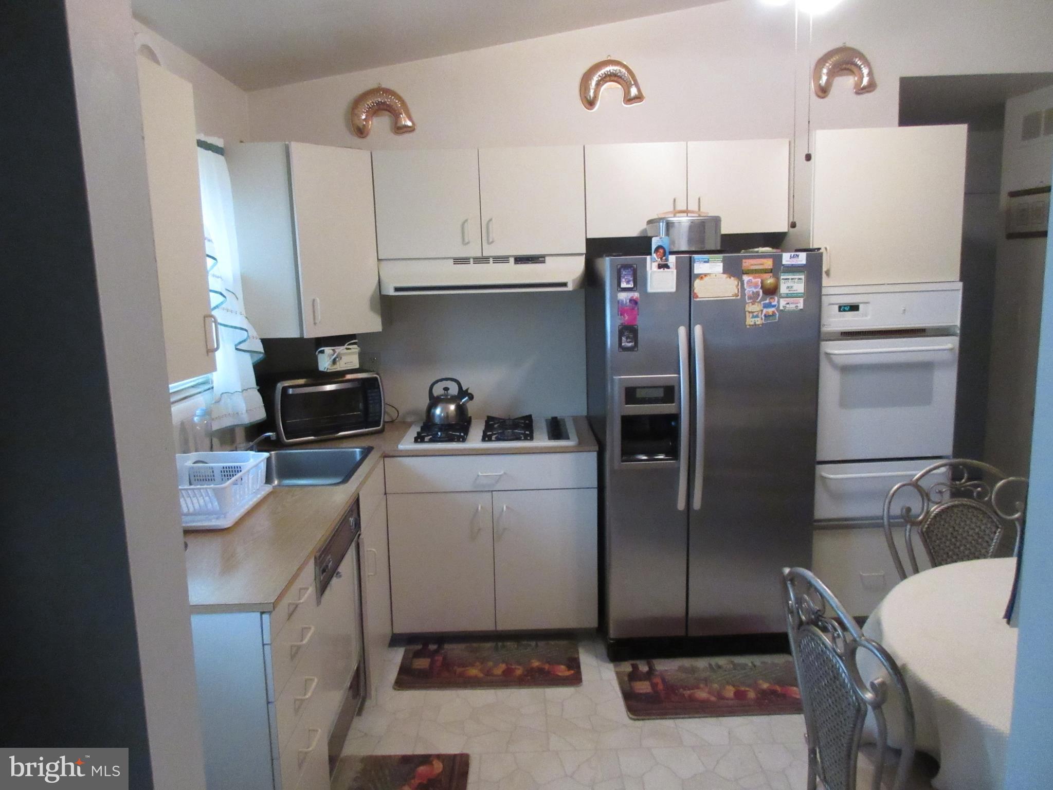 4786 Byron Road Baltimore, MD 21244 - Photo 7 of 30 a kitchen with a refrigerator a stove a sink and cabinets