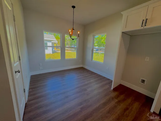 a view of an empty room with window and wooden floor