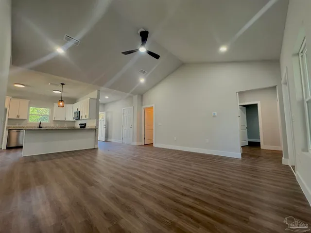 a view of an empty room and a kitchen