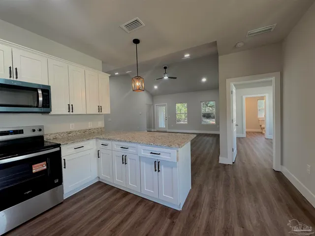 a kitchen with granite countertop wooden floors and white cabinets