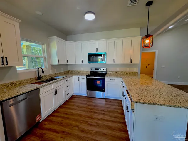 a kitchen with granite countertop wooden floors appliances and sink