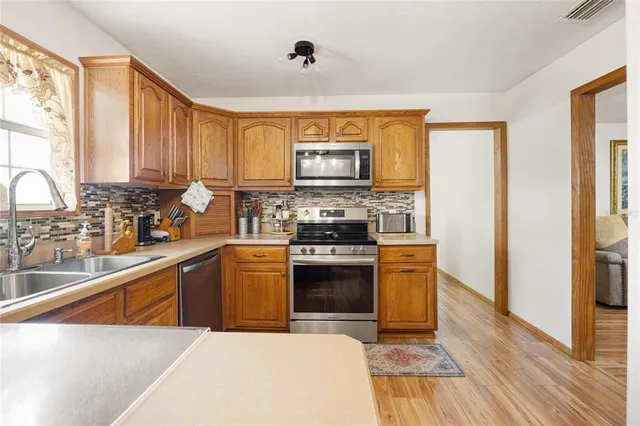 a kitchen with stainless steel appliances granite countertop a stove a sink dishwasher and a refrigerator