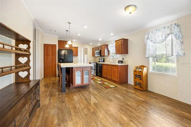 a open kitchen with stainless steel appliances granite countertop a refrigerator oven stove a dining table and chairs with wooden floor