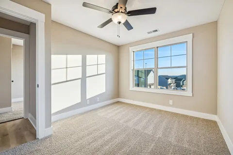 an empty room with windows and ceiling fan