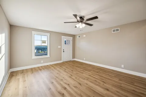 a view of an empty room with wooden floor and a window