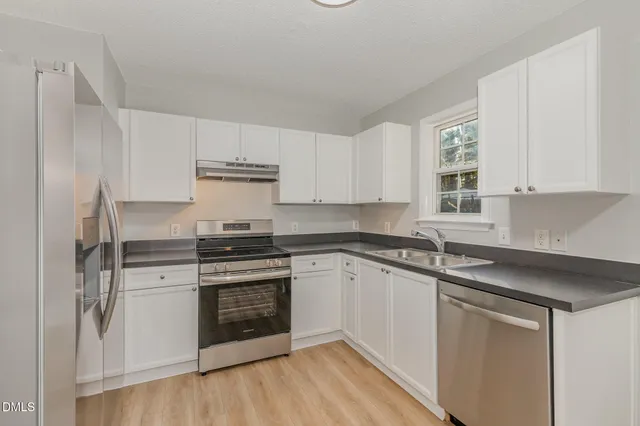 a kitchen with a refrigerator a stove top oven and wooden floor