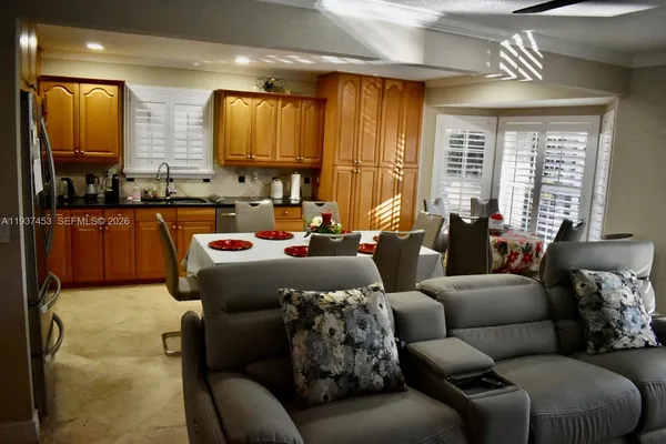 a kitchen with stainless steel appliances a sink a stove a refrigerator wooden floor and a dining table