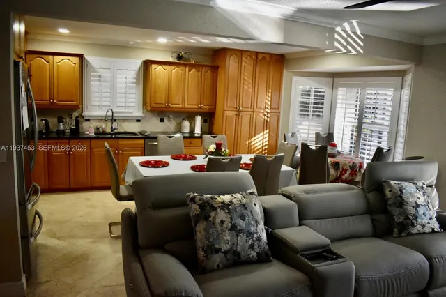 a kitchen with stainless steel appliances a sink a stove a refrigerator wooden floor and a dining table