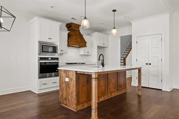 a kitchen with stainless steel appliances granite countertop a sink a stove a refrigerator and wooden floor