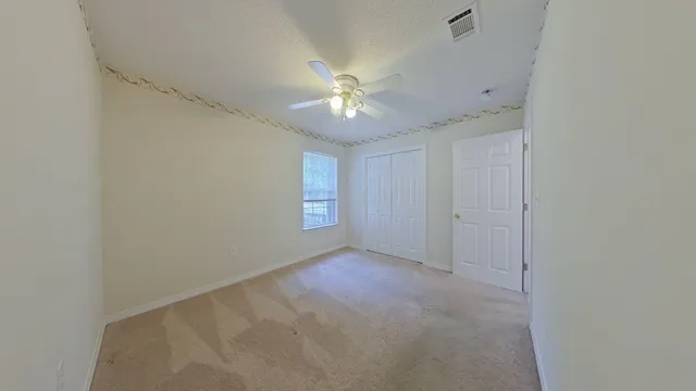 an empty room with a window and a fan