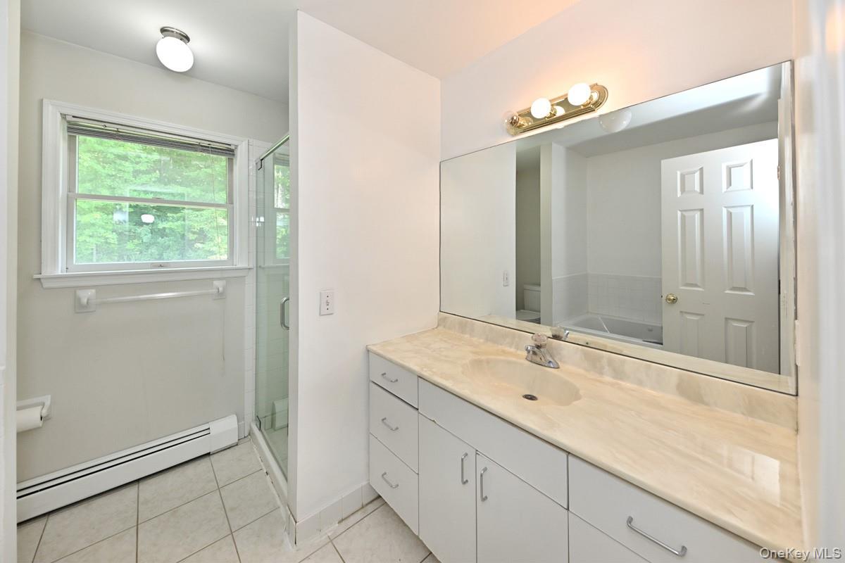 14 Roble Road Suffern, NY 10901 - Photo 24 of 30 Full bathroom with a baseboard radiator, vanity, a shower stall, and tile patterned flooring