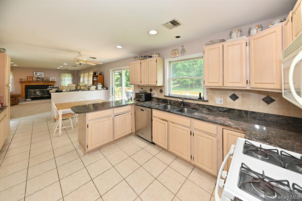 14 Roble Road Suffern, NY 10901 - Photo 9 of 30 Kitchen featuring white appliances, recessed lighting, a glass covered fireplace, light brown cabinets, and a peninsula
