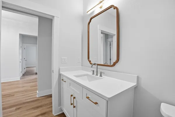 a bathroom with a granite countertop toilet a sink and a mirror