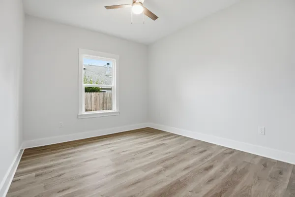 an empty room with wooden floor and a ceiling fan
