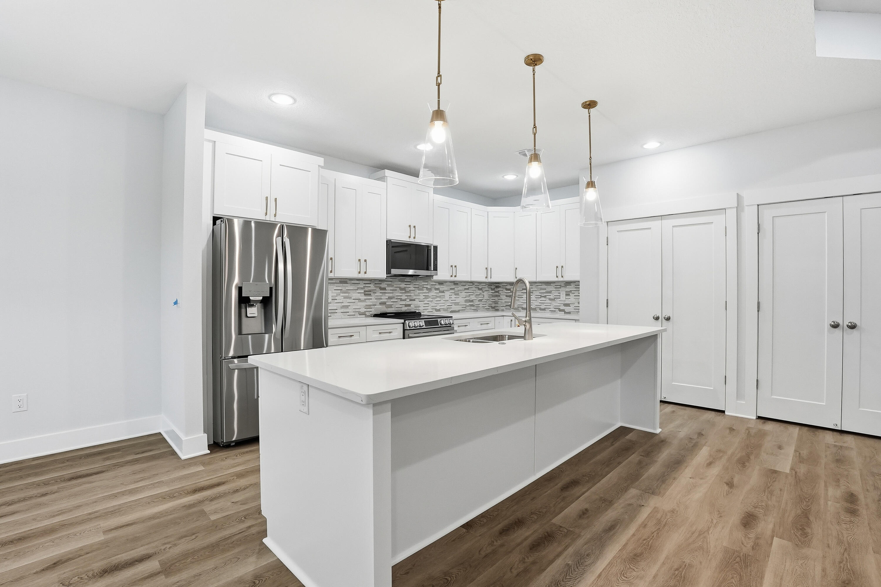 15 Plew Avenue Shalimar, FL 32579 - Photo 32 of 67 a large kitchen with kitchen island a stove a sink dishwasher a refrigerator and cabinets with wooden floor