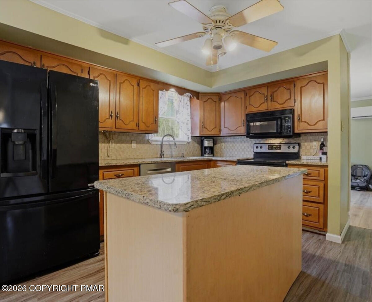 239 Sundance Road Effort, PA 18330 - Photo 10 of 60 a kitchen with granite countertop a refrigerator a sink a stove a microwave and island with wooden floor