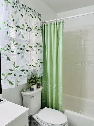 a white toilet sitting next to a bathroom sink and a shower curtain