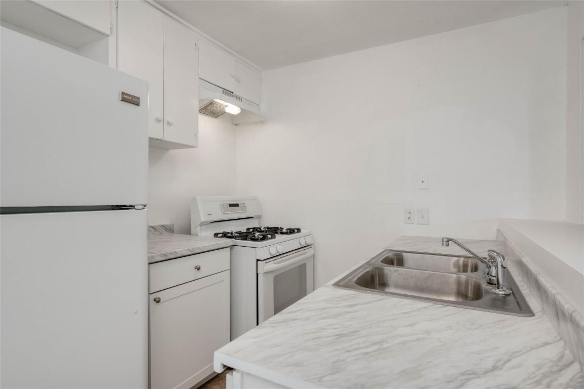 1303 East St Johns Avenue Austin, TX 78752 - Photo 13 of 30 a kitchen with a sink stove and cabinets
