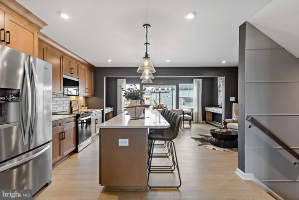 a view of a kitchen with kitchen island stainless steel appliances refrigerator stove dining table and chairs