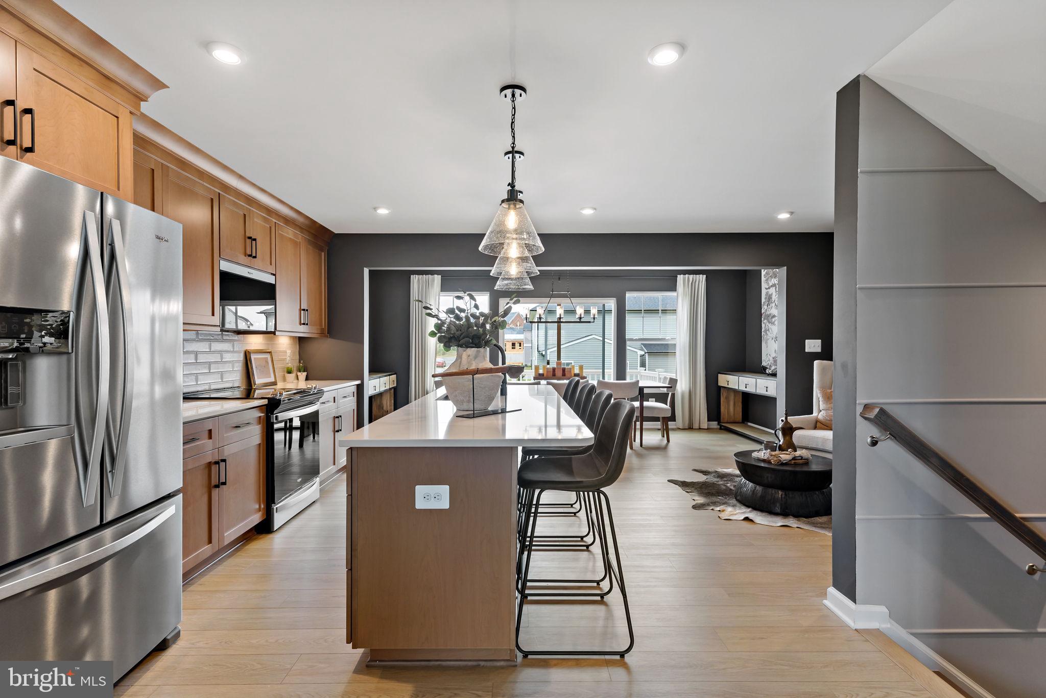 a view of a kitchen with kitchen island stainless steel appliances refrigerator stove dining table and chairs
