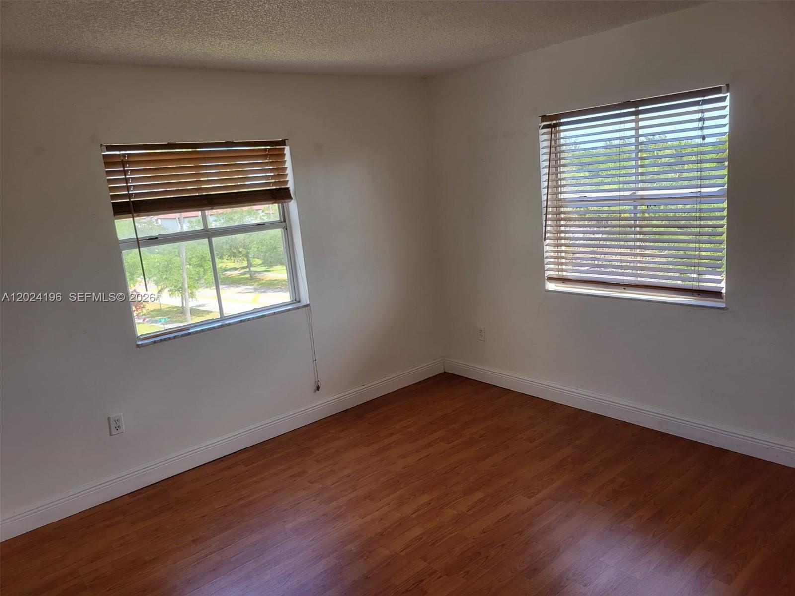 8260 Southwest 210th Street, Unit 319 Cutler Bay, FL 33189 - Photo 7 of 20 a view of an empty room with wooden floor and a window