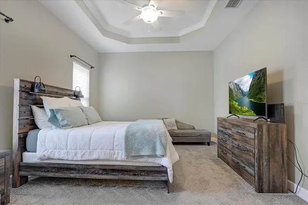a bedroom with a bed and a flat tv screen on dresser