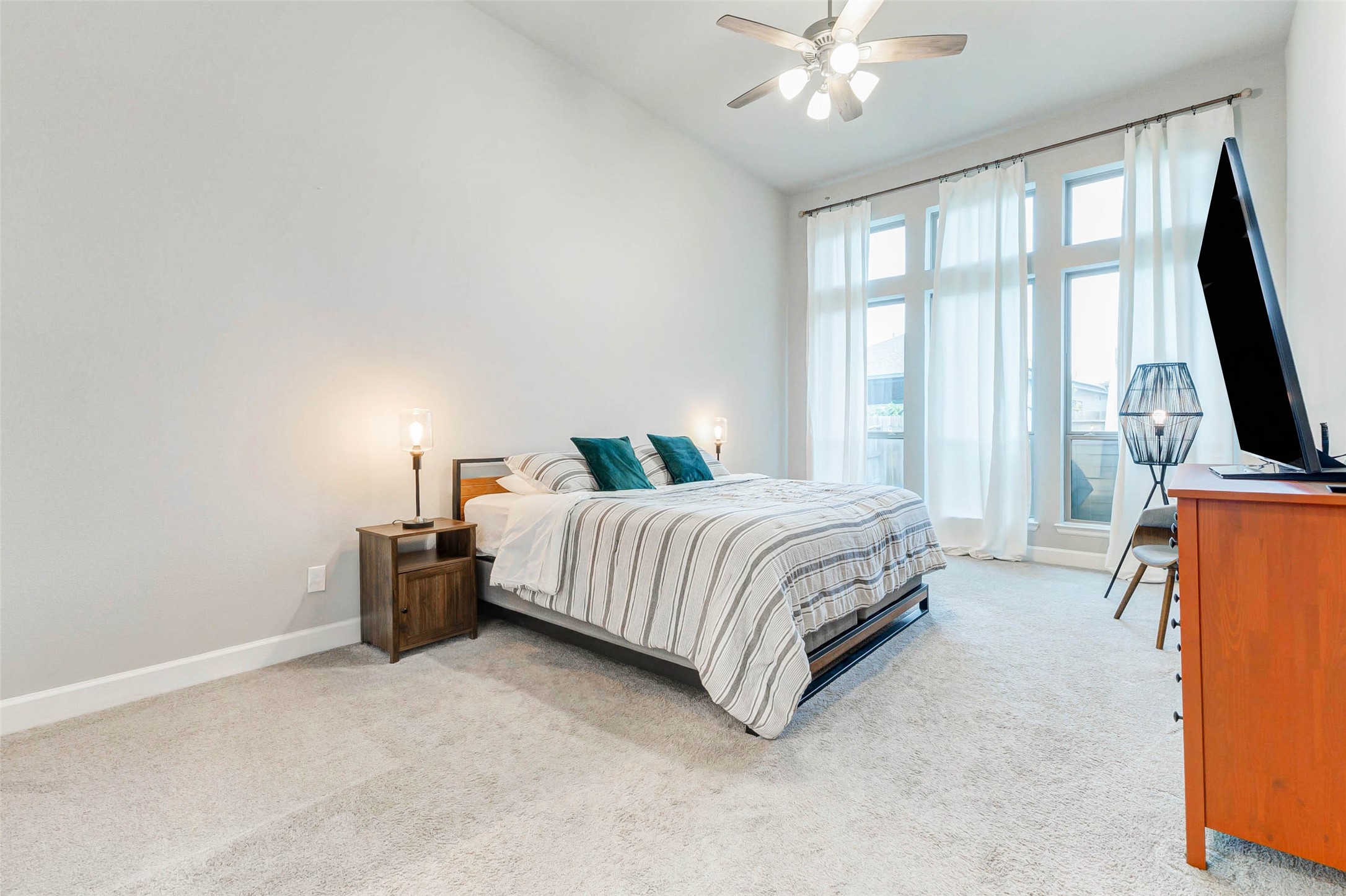 4714 Southpoint Way Fulshear, TX 77441 - Photo 17 of 45 a spacious bedroom with a bed a flat screen tv and a chandelier