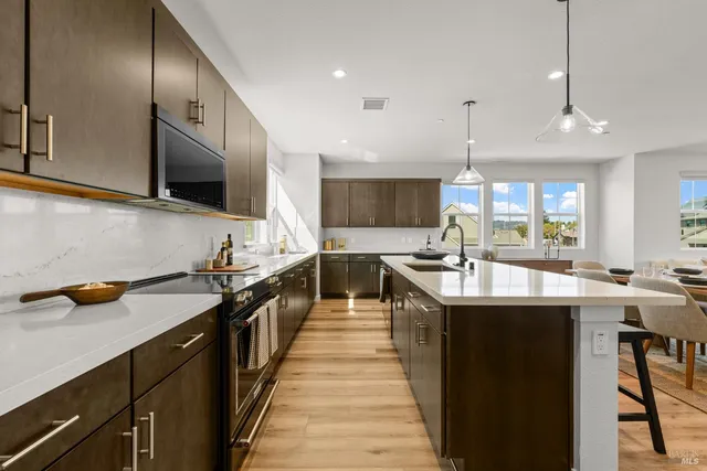 a kitchen with stainless steel appliances granite countertop a sink and a wooden floors