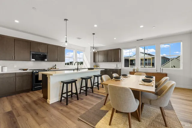 a large kitchen with kitchen island a dining table chairs and a stove top oven
