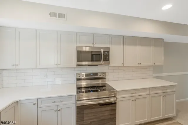 a kitchen with white cabinets and stainless steel appliances