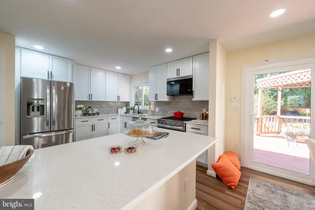 a kitchen with granite countertop a refrigerator stove and sink with wooden floors
