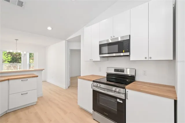 a kitchen with stainless steel appliances granite countertop white cabinets and a stove top oven