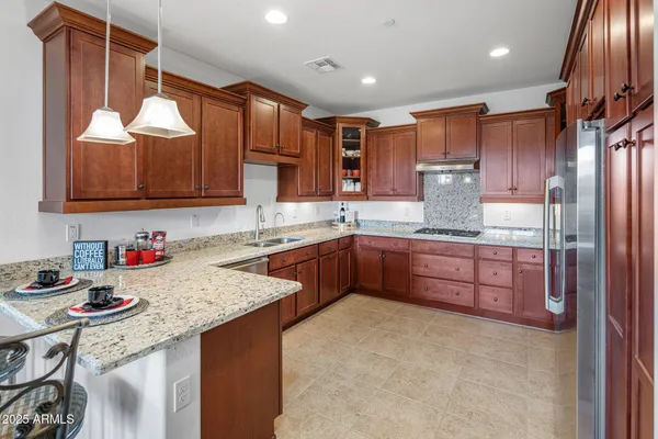 a kitchen with stainless steel appliances granite countertop a sink refrigerator and cabinets