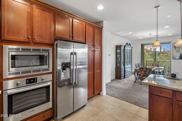 a kitchen with stainless steel appliances a stove a refrigerator and a sink with wooden cabinets