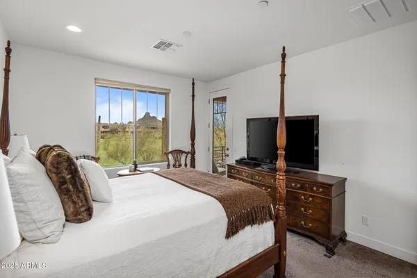 a bedroom with a bed and a flat tv screen on the dresser
