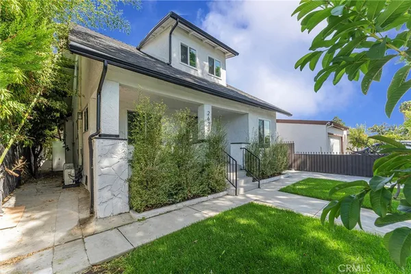 a view of a house with a yard plants and large tree