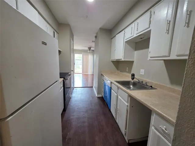 a kitchen with sink a refrigerator and wooden cabinets