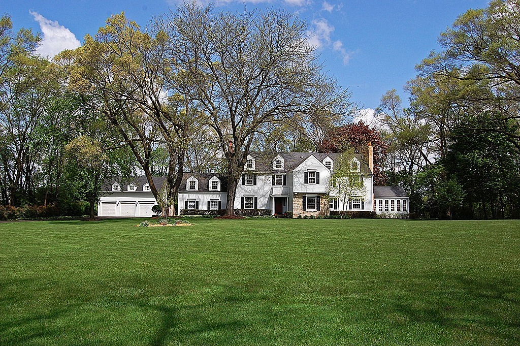 a view of a white house with a big yard and large trees