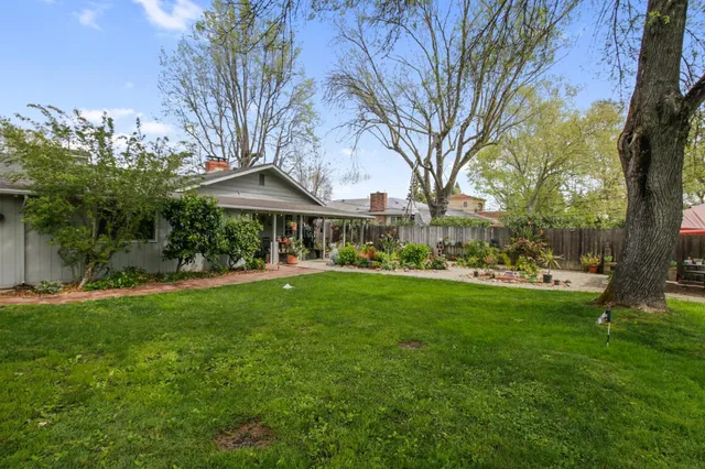 a view of house with a yard and potted plants