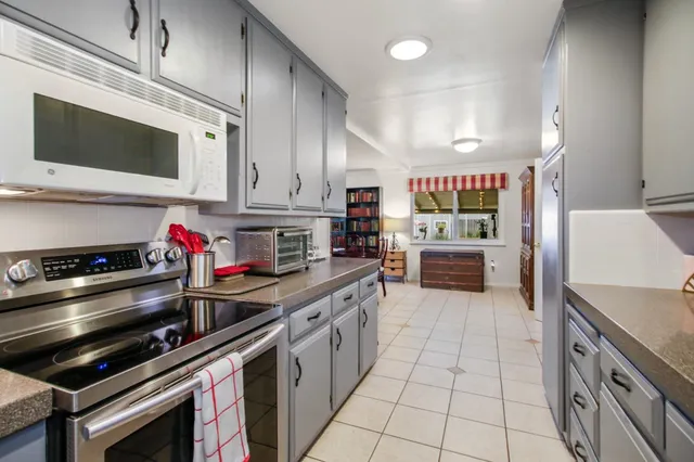 a kitchen with stainless steel appliances kitchen island granite countertop a stove a microwave and a sink