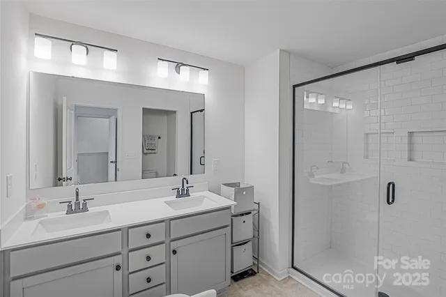 a bathroom with a double vanity sink mirror and shower