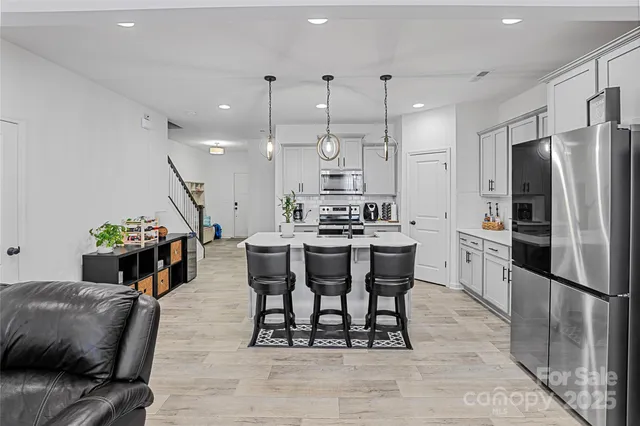 a kitchen with stainless steel appliances kitchen island granite countertop a dining table chairs refrigerator and sink