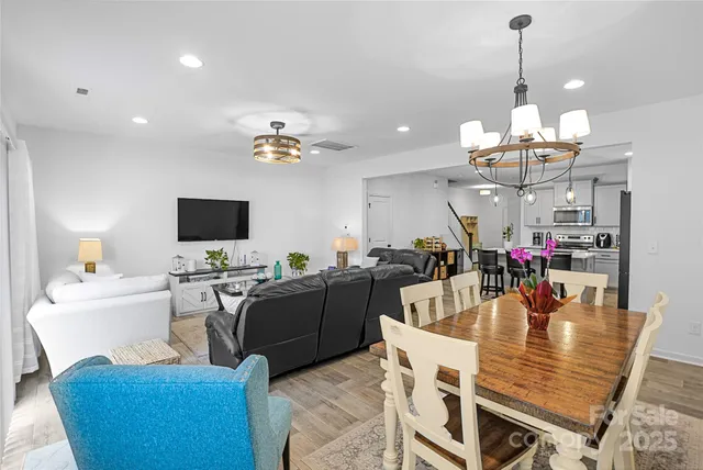 a dining room with wooden floor a chandelier a wooden table and chairs