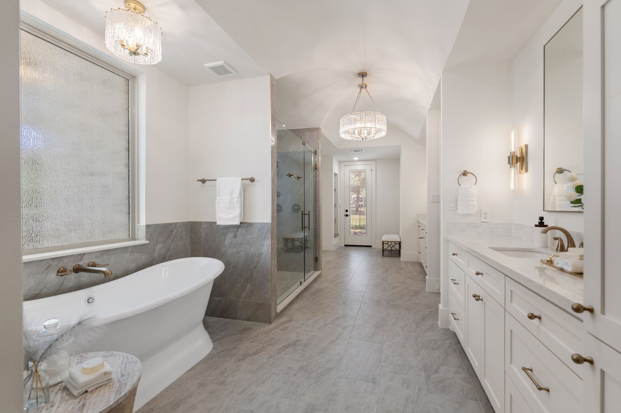 31 Hollymead Drive Spring, TX 77381 - Photo 24 of 50 This spacious bathroom features a luxurious freestanding tub, a large glass-enclosed shower, and elegant dual vanities. The room is beautifully lit with modern fixtures and natural light from the window, offering a serene and stylish retreat.