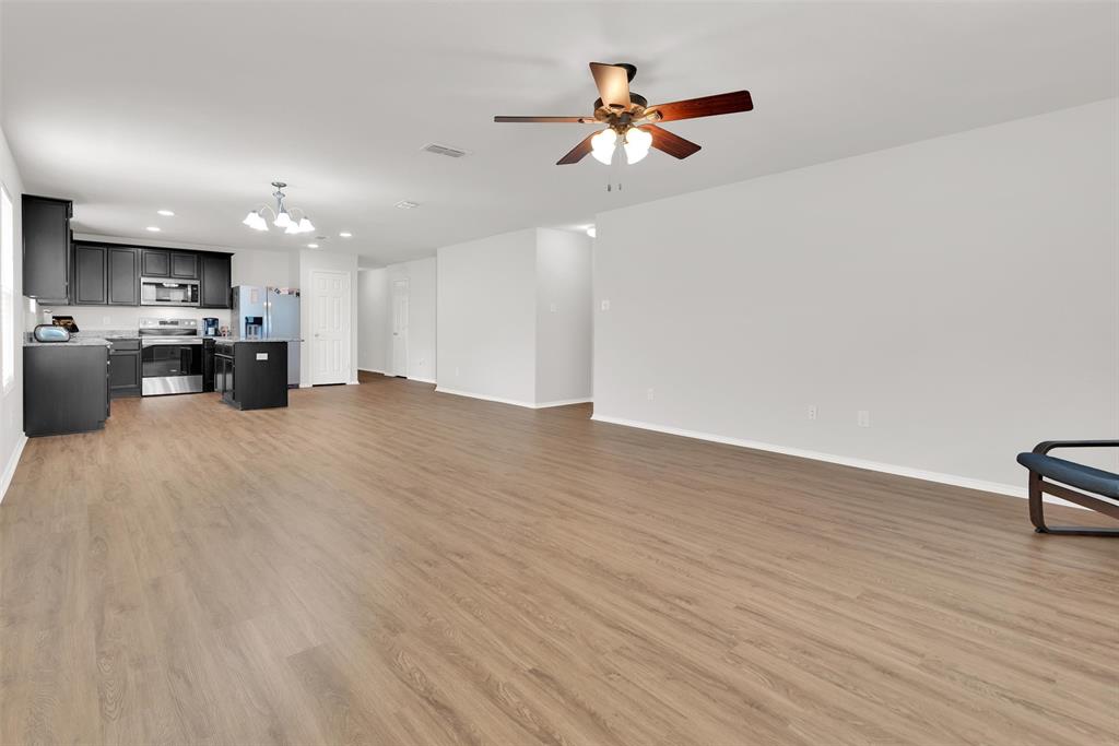 3011 Hickory Ridge Melissa, TX 75454 - Photo 15 of 30 Open-concept living area featuring wood-finish flooring, a kitchen with dark cabinetry, stainless steel appliances, and a ceiling fan with integrated lighting